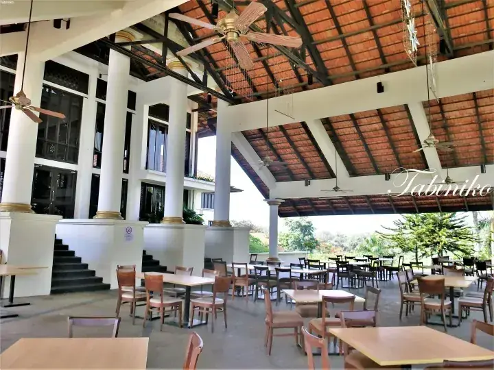 Spacious open-air dining area with wooden tables, white pillars, and terracotta roof at a Malaysian resort