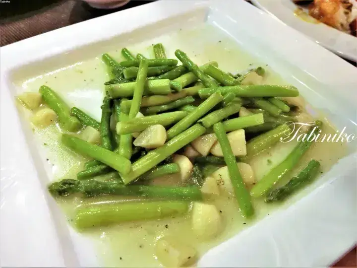 Creamy green curry with fresh asparagus and mushrooms served on a white square plate.