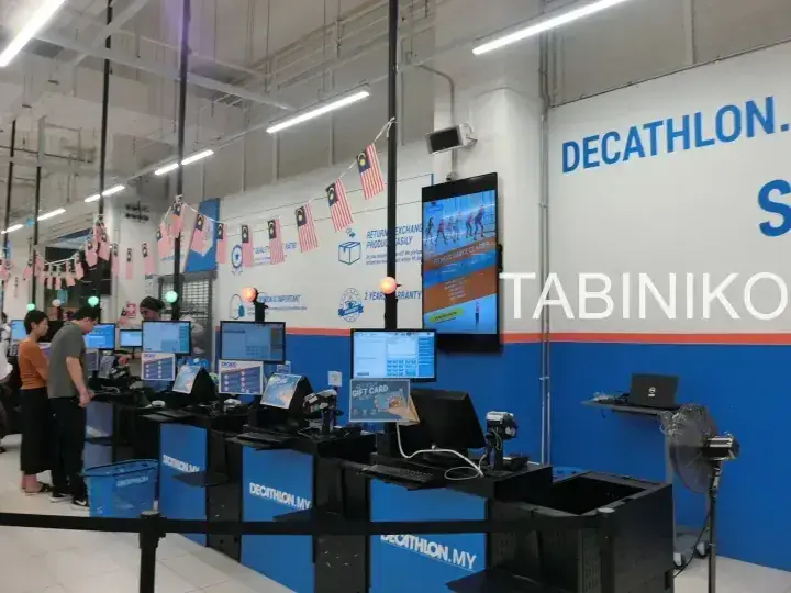天井からマレーシア国旗が飾られたデカトロン店舗のレジカウンターとデジタルスクリーン。