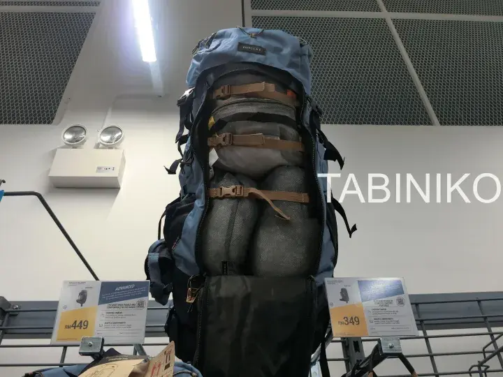 Large blue hiking backpack with compression straps displayed on a store rack, priced at RM449.