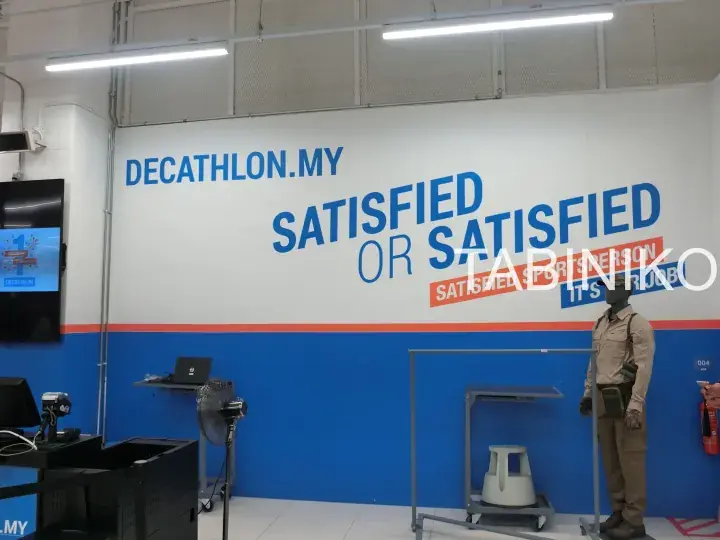 Interior of a Decathlon store showing the slogan “Satisfied or Satisfied” on the wall.