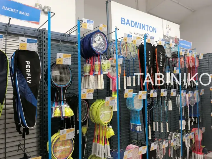 Display of Perfly badminton rackets and racket bags in a retail store with signage for the badminton section.