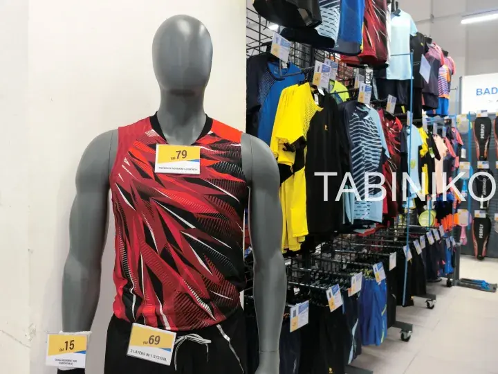 Mannequin wearing a red and black sports shirt with a price tag in a Decathlon store.