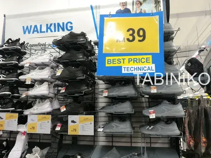Decathlonの店内で、技術的なウォーキングシューズの最安値RM39を示す黄色い看板が設置された靴の陳列。