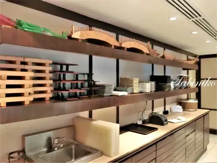 Shelves displaying wooden bridge models and stacks of plates in a restaurant interior.