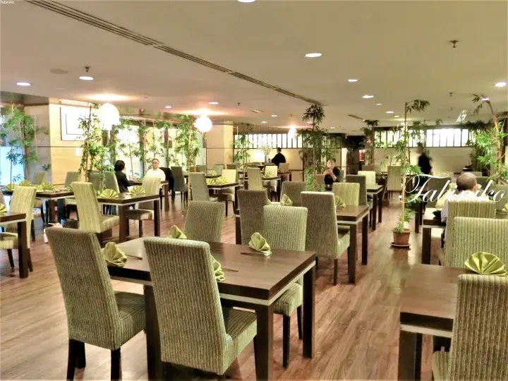 木製テーブルと緑のストライプ椅子、竹の植物が配置された広々としたダイニングエリア。