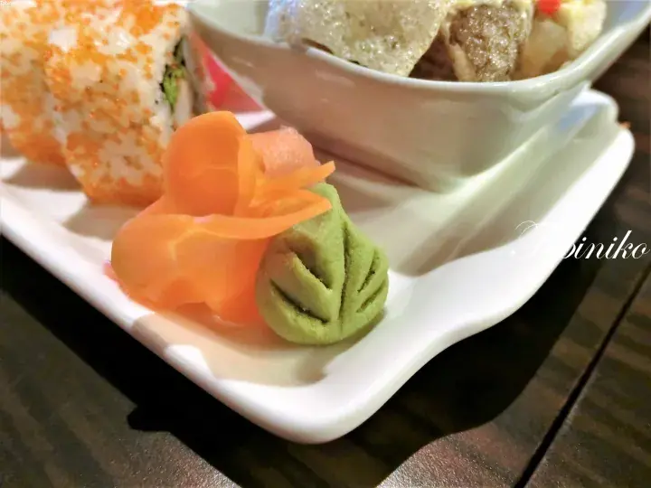 寿司ロール、生姜、わさび、そして揚げ豆腐と肉団子のサイドディッシュが盛られたお皿。