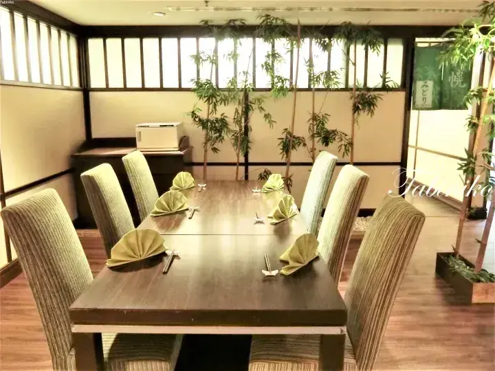 Private dining room with wooden table, green chairs, and bamboo decor at Midori restaurant.