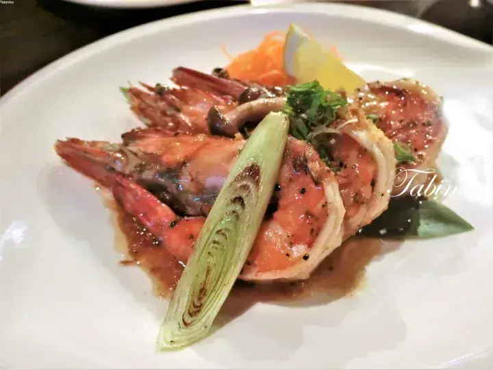 Grilled prawns and scallops served with lemongrass and garnish on a white plate