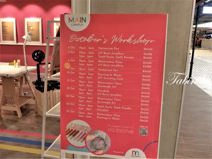 A red poster board displaying October&rsquo;s workshop schedule at MAIN Campus, featuring classes like Herbarium Pen and UV Resin Jewellery.