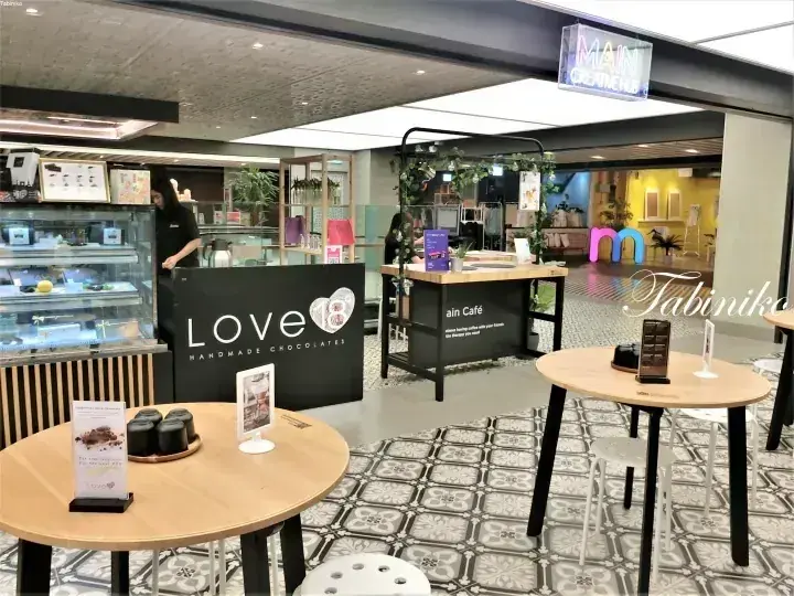 Main Creative Hub内のLove Handmade Chocolatesカフェの店内。ショーケースやテーブル、看板が見える。