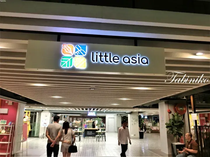 The entrance to Little Asia food court with illuminated signage and shoppers walking inside.