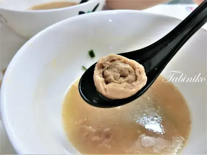 スプーンで持ち上げられた豚肉団子の断面が映る白碗の豚肉団子スープ。