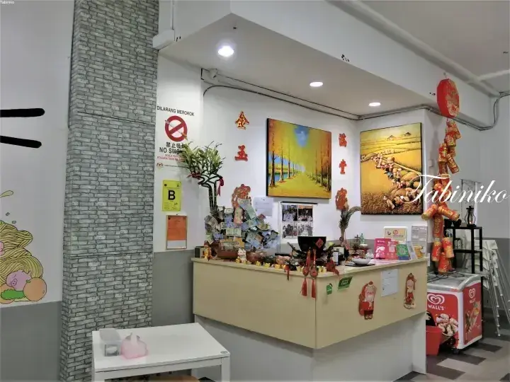 禁煙標識や装飾品が置かれた、金色のアクセントとアートワークが特徴的なマレーシアの物件の受付カウンター。