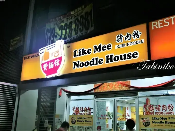 イラストのラーメンボウルロゴと中国語の文字が特徴的な「Like Mee Noodle House」の夜間店舗看板。