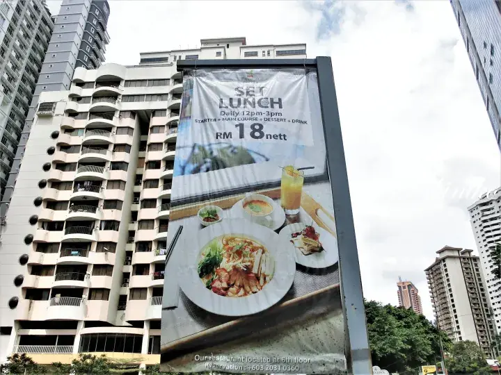 Large outdoor banner advertising a RM18 set lunch at a restaurant located on the 6th floor of a high-rise building in Malaysia.