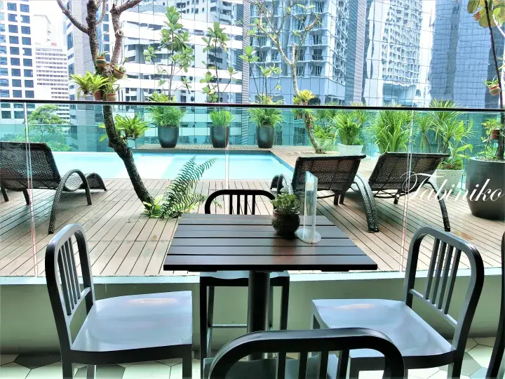 Modern rooftop terrace with wooden deck, pool, and city skyline view at a Kuala Lumpur property