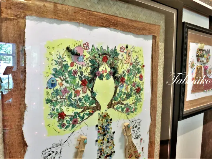 A framed mixed-media artwork featuring a tree with a human silhouette, decorated with beads and colorful patterns.