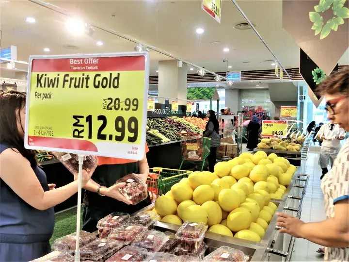 A promotional sign for Kiwi Fruit Gold priced at RM12.99 per pack in a Malaysian supermarket fruit section.