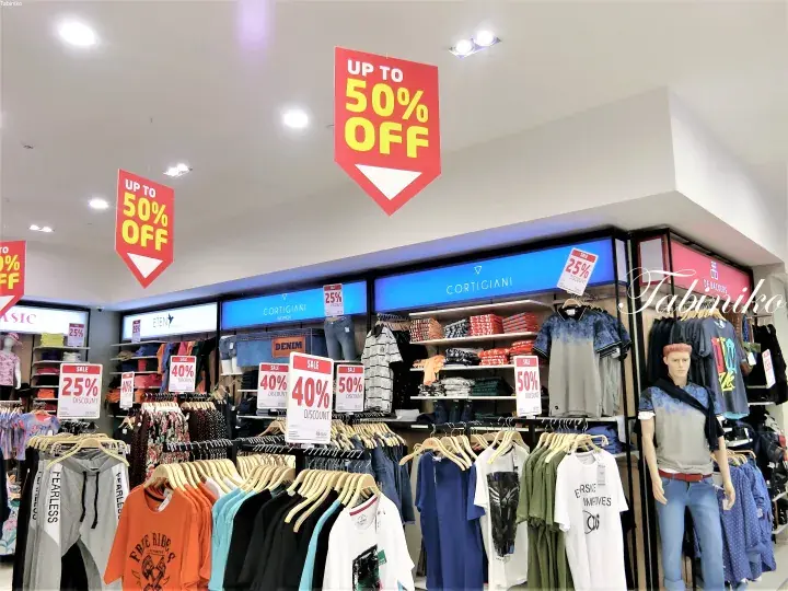 Cortigiani clothing store interior with racks of apparel and hanging signs advertising up to 50% off sale.