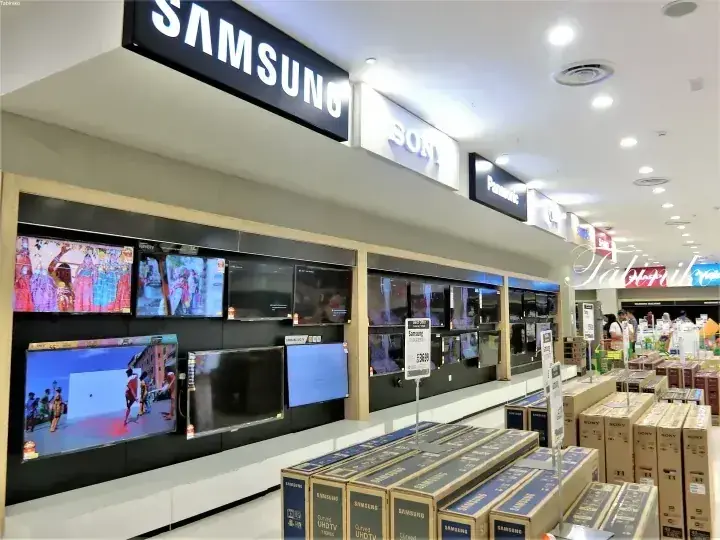 Samsung、Sony、Panasonicのテレビが展示された家電量販店の店内。床には箱が積み上げられている。