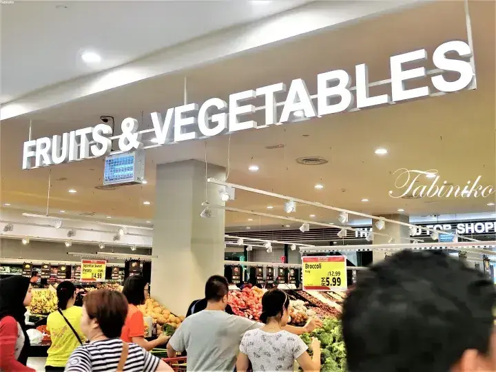 マレーシアのスーパーマーケットで果物・野菜売り場を買い物する顧客たち。