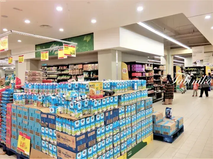 マレーシアのスーパーマーケットで棚に積まれたFresh Krim牛乳のパッケージと買い物客の姿。
