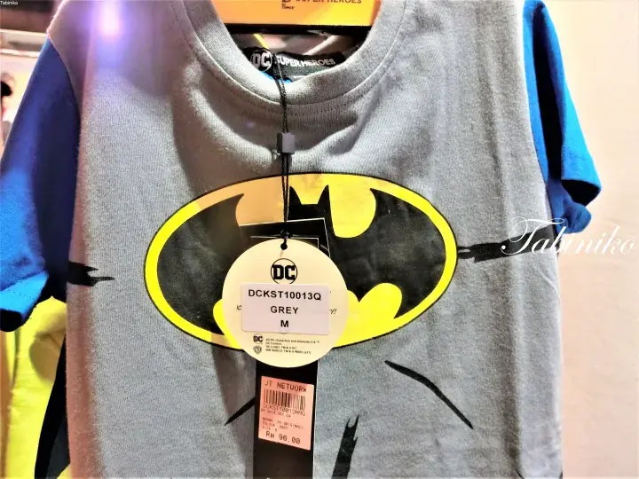 Grey and blue Batman t-shirt with DC logo tag and RM96.00 price sticker hanging on a rack