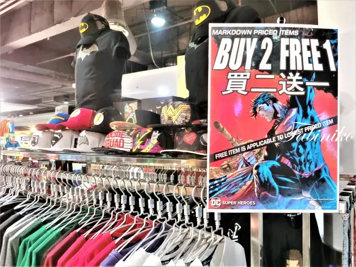 A store display featuring DC Super Heroes merchandise with a Buy 2 Free 1 promotional sign.