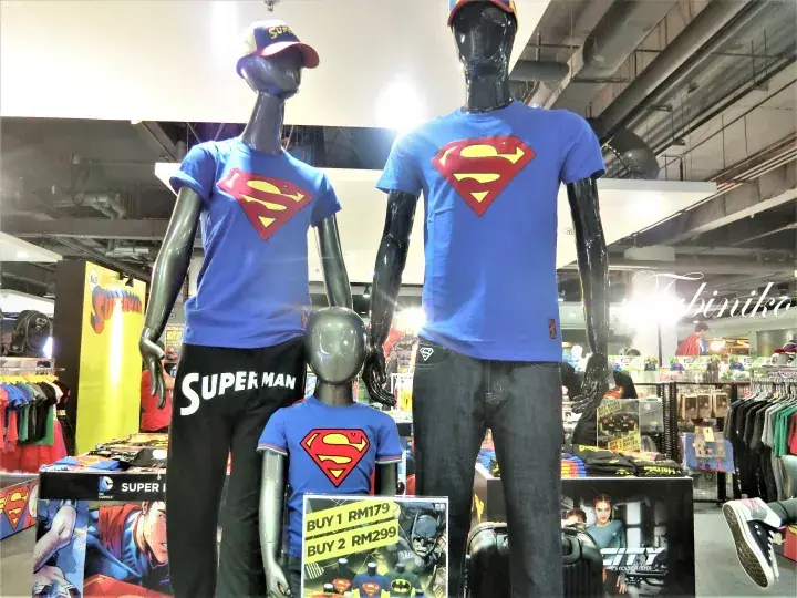 Mannequins wearing Superman merchandise at a store display with promotional pricing signs.