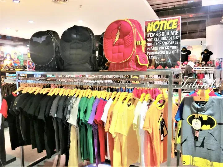 Colorful superhero t-shirts and themed backpacks displayed on racks at a retail store.