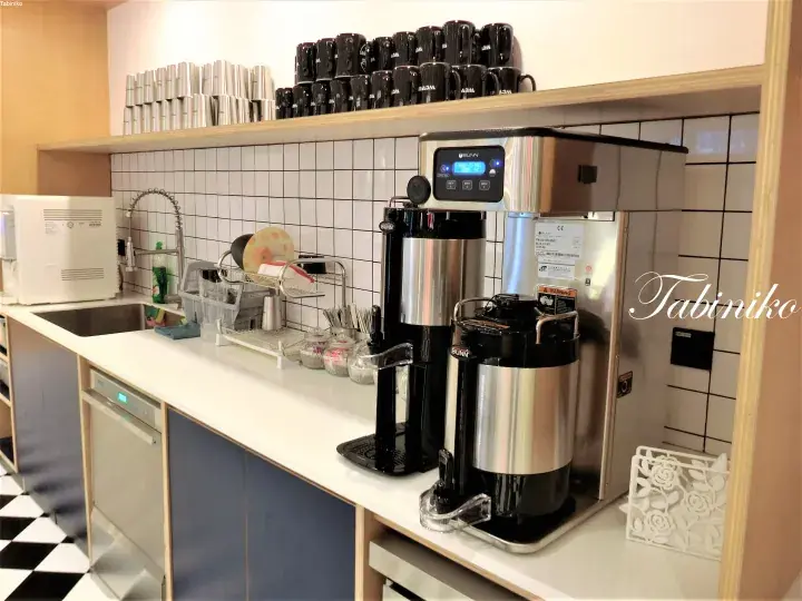 Modern kitchenette with coffee machines, water dispenser, and dish rack in a property.