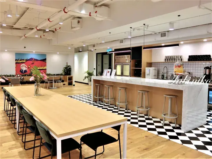 Modern co-working space with long wooden table, bar counter, and checkered floor.