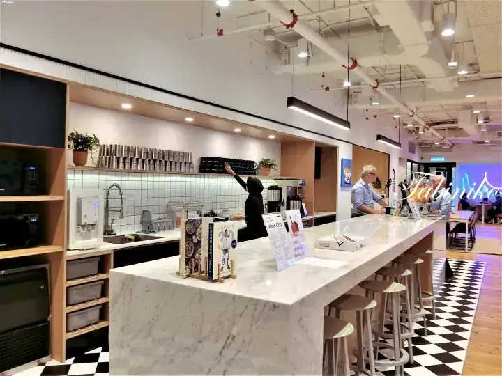 大理石のカウンターとチェック柄の床が特徴的な、明るく開放的な共用キッチンと調理スペース。