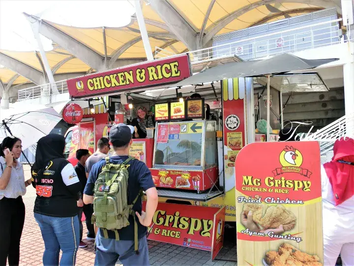 Customers queue at Mc Grispy Chicken & Rice stall under a large canopy.