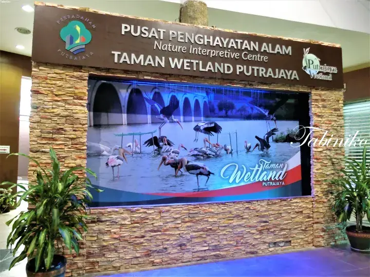 Sign for Pusat Penghayatan Alam Nature Interpretive Centre at Taman Wetland Putrajaya featuring a bird display.