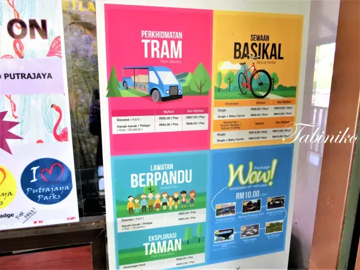 Information board at Putrajaya Parks showing rates for Tram Service, Bicycle Rental, Guided Tour, and Wow! Package.