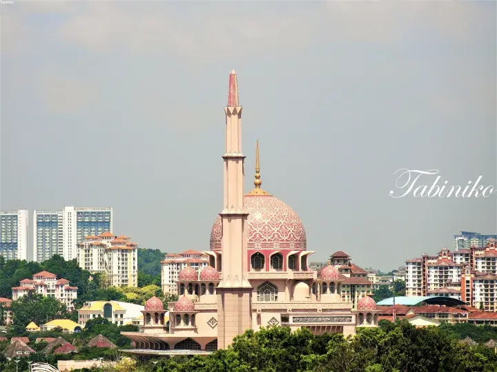 Pink Putra Mosque in Putrajaya with its distinctive dome and minaret against the city skyline.