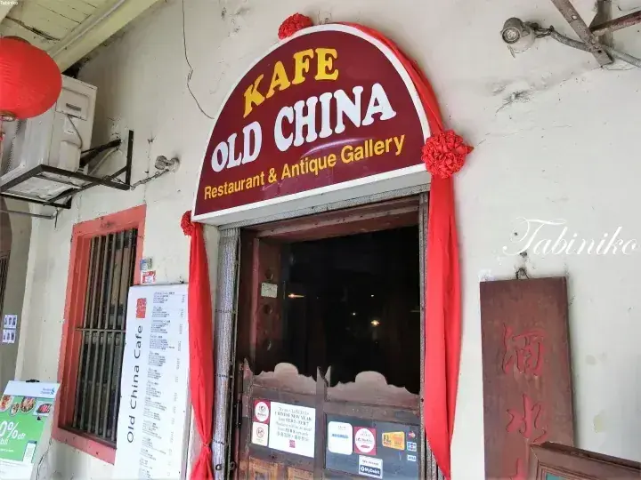 赤い提灯と木製の扉が特徴的な、Kafe Old China Restaurant & Antique Galleryの入り口。