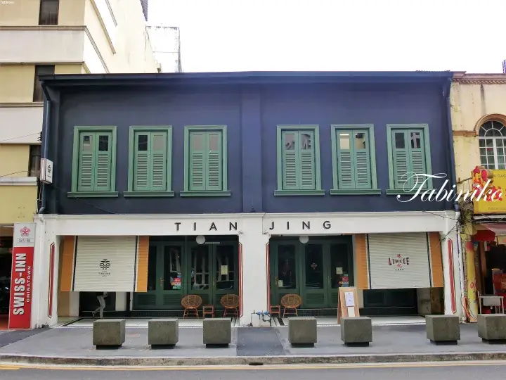 Tian Jing shophouse facade with green shutters and white ground floor signage in a Malaysian street setting.