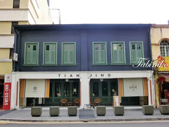 緑色のシャッターと白い1階の看板が特徴的なTian Jingの店屋敷の外観。