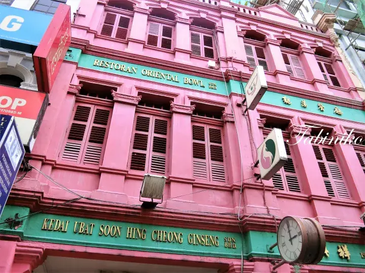 Pink heritage shophouse facade in Kuala Lumpur featuring signs for RESTORAN ORIENTAL BOWL and KEDAI UBAT SOON HING CHEONG GINSENG SDN BHD.