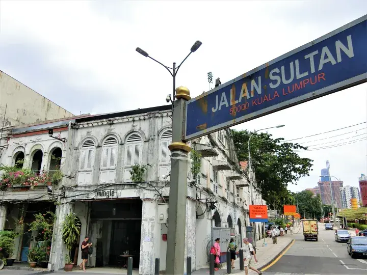 Jalan Sultan street sign in Kuala Lumpur with heritage shophouses and pedestrians along the road.
