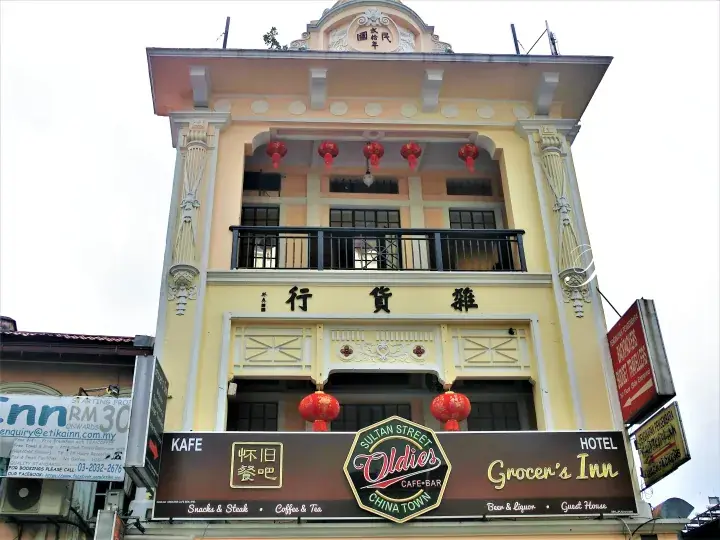 The yellow facade of Grocer&rsquo;s Inn hotel in Chinatown featuring Oldies Cafe-Bar signage and traditional Chinese lanterns.
