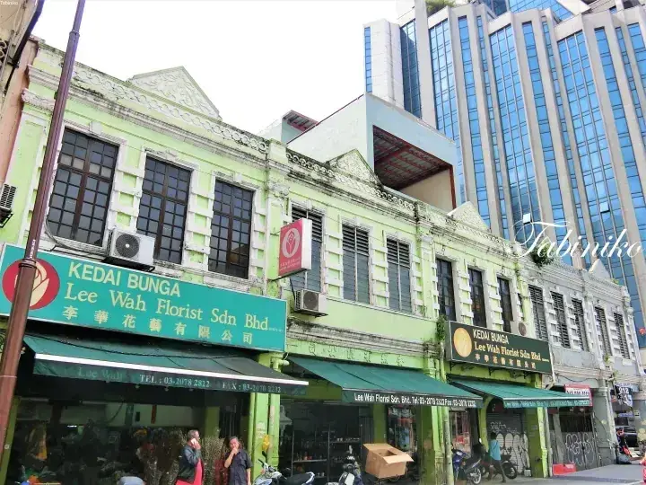 背景に高層ビルを配した緑色の古民家風ショップハウス、看板には「Lee Wah Florist Sdn Bhd」と表示。