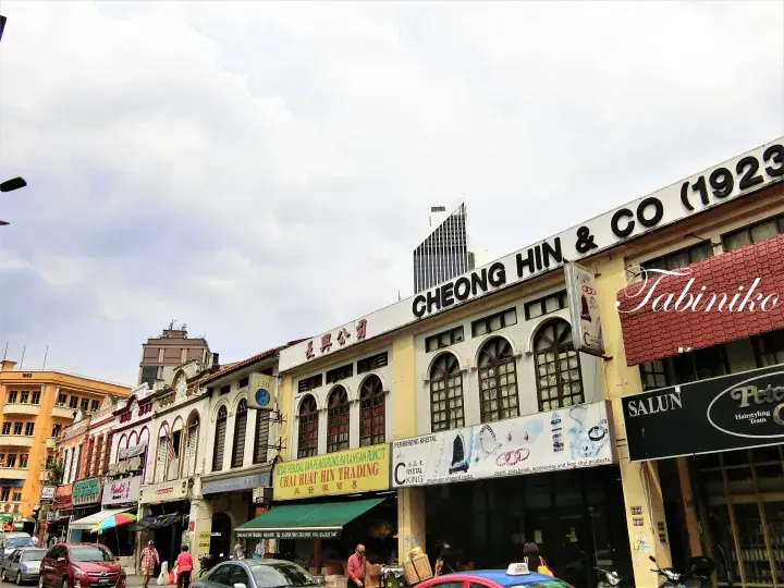 Historic Cheong Hin & Co building facade on a street in Kuala Lumpur with other shophouses.