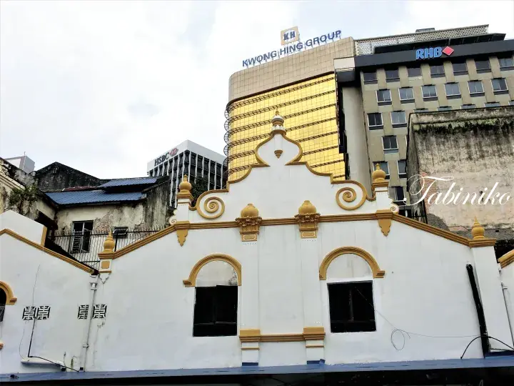 White colonial building with gold trim in front of Kwong Hing Group and RHB buildings in Kuala Lumpur.