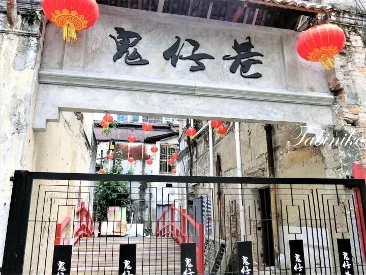 伝統的な中国文字と赤い提灯が飾られた、風化した外観の「鬼仔巷」の入口ゲート。