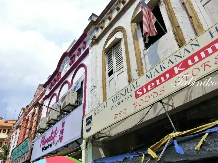 マレーシアの伝統的な/shop/と「Siew Kum Hor Foods」の看板、マレーシア国旗が掲げられた街並み。
