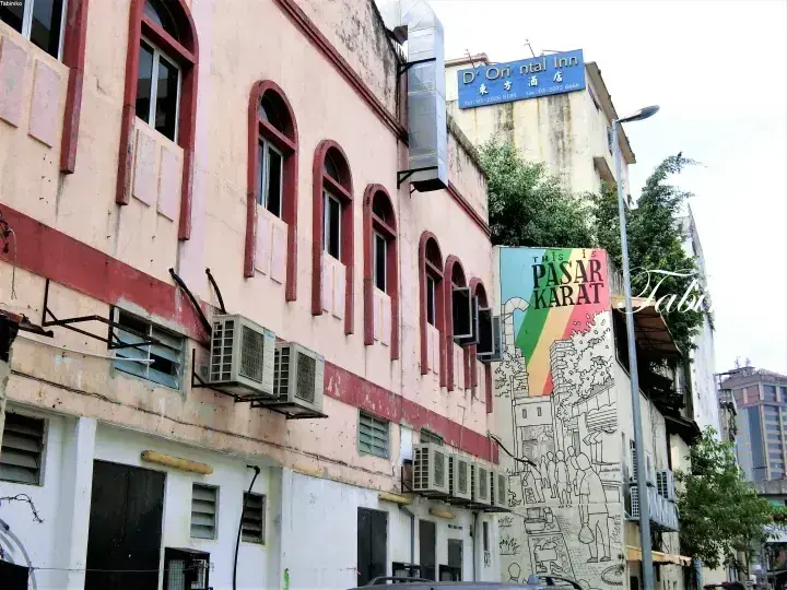 マレーシアの歴史的なショップハウスに描かれた「PASAR KARAT」の壁画と、その上の「D’ Oriental Inn」ホテルの看板。